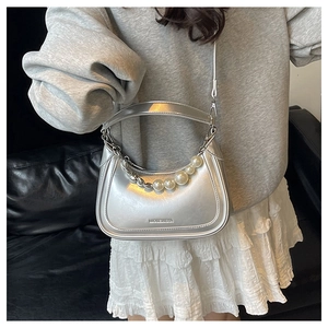 Close-up of metallic silver crescent bag featuring elegant pearl chain and logo details