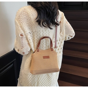 Close-up of a woven knit bucket bag with brown leather handles and a minimalist logo tag