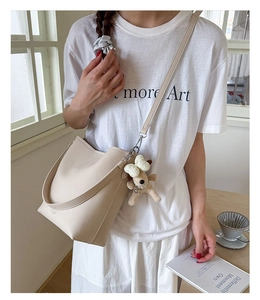 Detail of cream pebbled leather bucket bag featuring a cute plush dog charm accessory