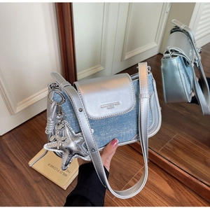 Detail of silver metallic leather and blue denim bag with a large star pendant charm