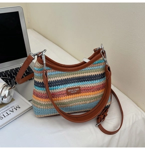 Détail du sac de plage en paille rayé avec finitions en cuir marron et crochets en métal