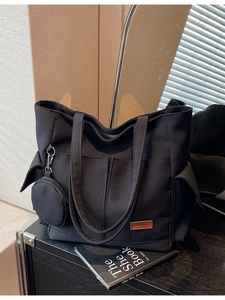 Minimalist black canvas tote bag with side pockets and a small round coin purse charm