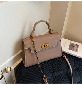 Close-up of taupe textured handbag featuring gold twist lock and metal chain strap