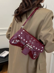 Bolso de hombro burdeos brillante con remaches plateados usado por una modelo