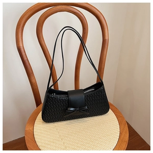 Detail of woven black leather texture with bow design on an elegant underarm bag