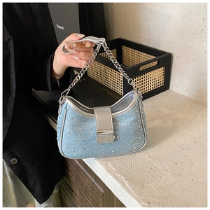 Detailed macro view of light blue denim bag featuring shiny rhinestones and silver chain strap