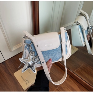 Detail of denim and leather crossbody bag featuring silver star and balloon dog charms