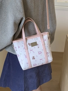 Mini tote bag with cartoon prints and pink handles worn as a crossbody by a model