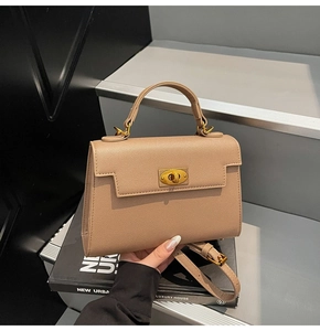 Detail of Saffiano leather texture and golden turn-lock on a beige structured handbag