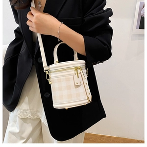 Beige quilted cylinder bucket bag shown on a model with gold hardware and a strap