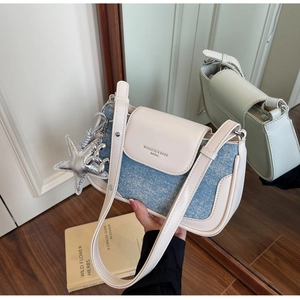 Close-up of cream leather and blue denim crossbody bag with starfish and balloon dog charms