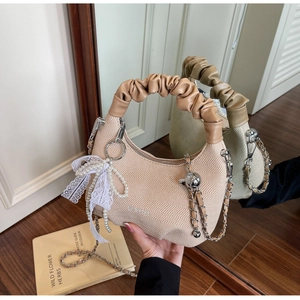 Detail of knit handbag featuring pearl pendant, lace bow, and silver metal chain strap