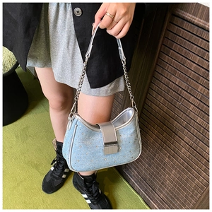 Detail of light blue denim underarm bag with sparkling silver rhinestones and chain strap