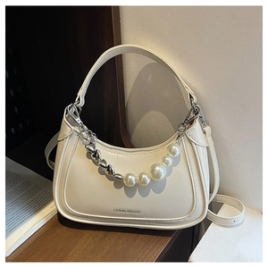 Detail of hobo bag featuring decorative silver heart charms and large white pearls
