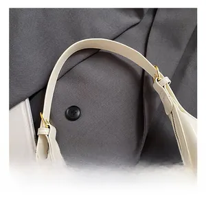Gros plan sur la bandoulière de sac crème avec boucle dorée et détails plissés
