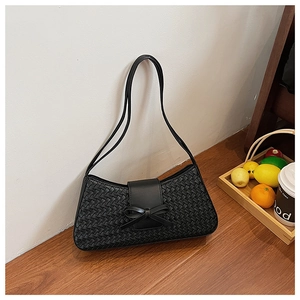 Detailed view of black woven texture underarm bag with decorative leather bow and straps