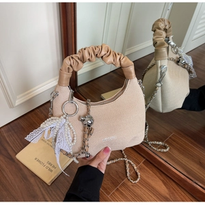Detail of apricot woven hobo bag with pearl lace pendant and silver metal chain strap
