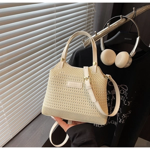 Detailed close-up of beige woven bucket bag with leather handle and adjustable shoulder strap