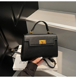 Close-up of black Saffiano leather bag with golden twist-lock on a designer book