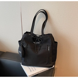 Detail of black canvas tote bag with drawstring closure and front zip pocket