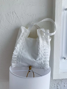 Minimalist large canvas tote bag featuring delicate white lace ruffle edges and wide straps