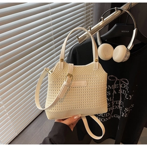 Close-up of cream woven bucket bag with leather handles and gold metal hardware