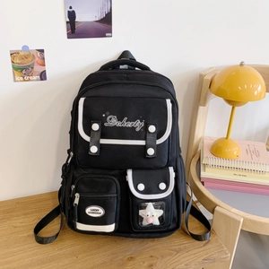 Vue détaillée du sac à dos en toile noire avec broderie, poches et breloque étoile en peluche