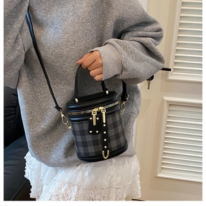 Close-up of diamond pattern cylinder bucket bag with gold zipper and leather strap