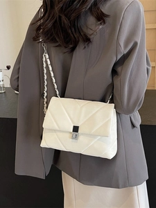 Fashionable white quilted crossbody bag with silver chain strap shown on a model