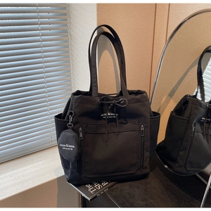 Detail of black canvas tote bag showing multi-pockets and mini coin purse attachment