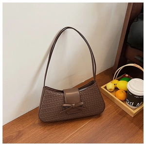 Detailed view of dark brown woven texture underarm bag with decorative leather bow