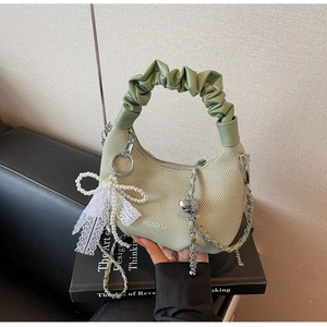 Detail of light green woven handbag with pearl bow charm and silver chain strap