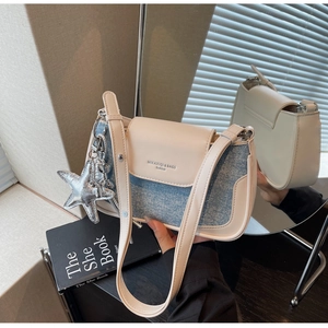 Detail of cream leather and blue denim patchwork bag with silver star charm