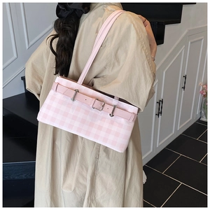 Detail view of pink and white checkered shoulder bag on model with leather strap