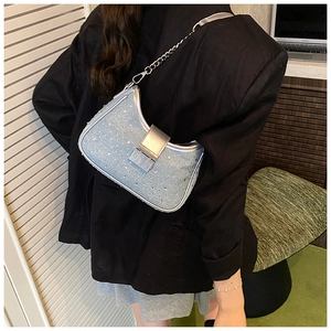 Detail of light blue denim crescent bag with sparkling rhinestones and silver chain strap