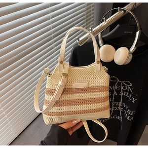 Detail of hand-woven striped straw bucket bag featuring a white leather logo and handle