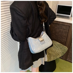 Detail of a sparkling rhinestone denim shoulder bag styled with a professional black blazer