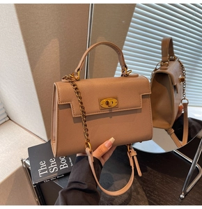 Detail of tan pebble leather Kelly bag with gold twist lock and mirror reflection