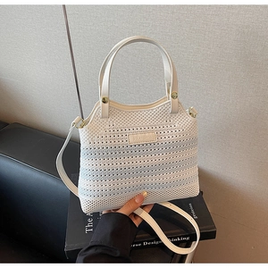 Close-up of knit texture and leather brand label on the off-white bucket bag