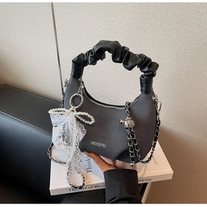 Detail of dark grey knit dumpling bag featuring a black scrunchie handle and silver chain
