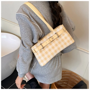 Detail shot of a yellow and white checkered shoulder bag with faux leather strap