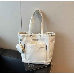 Detail of off-white canvas tote bag with drawstring closure and front pocket setup
