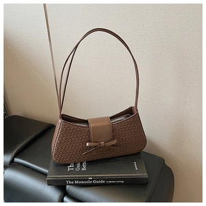 Detail of brown woven hobo bag with a decorative bow and textured leather shoulder strap