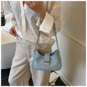 Detail of light blue denim rhinestone moon bag with silver chain strap on model