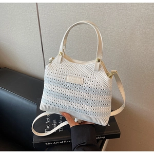 Detail of white knit bucket bag with blue stripes and elegant golden hardware