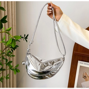 Close-up of silver crescent dumpling bag with metallic finish and knot detail