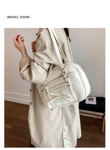 Close-up of cream white leather tote featuring heart bow and scalloped trim detail
