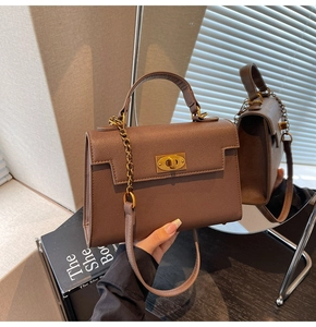 Close-up of a chocolate brown leather trapezoid bag with golden twist-lock and chain strap