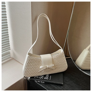 Detailed view of cream woven shoulder bag with leather strap and decorative bow design