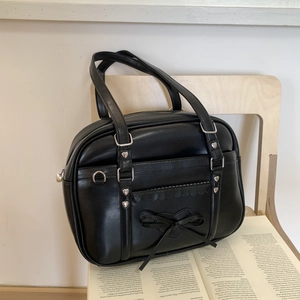 Detail of JK style black PU leather tote bag with heart rivets and bow on wooden chair